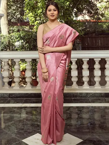 A soft pink saree with delicate buti work, worn by a model in a graceful outdoor setting. This piece is an example of our collection's understated and sophisticated options.