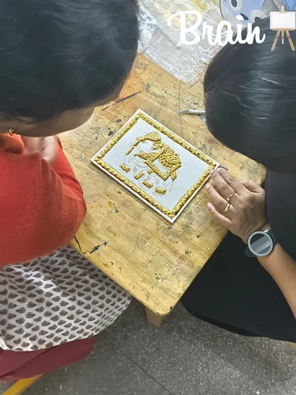 I'm showing a student how to properly set the gold foil on her small Tanjore artwork, ensuring a clean and professional finish.