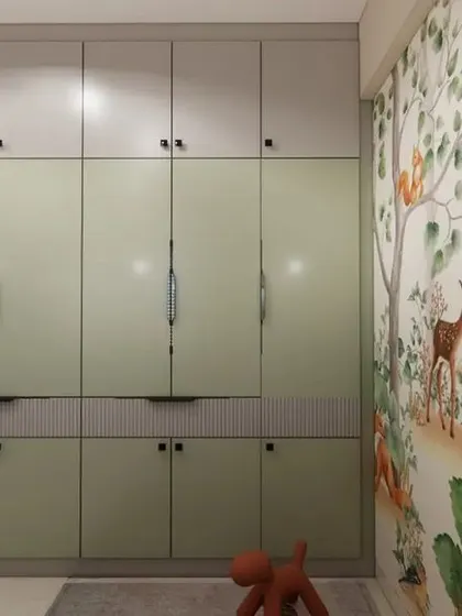 This angle highlights the ample storage provided by the floor-to-ceiling wardrobe in a soft pastel green, keeping the room clutter-free.
