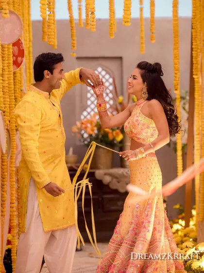 A sweet, candid moment between the couple during their Haldi ceremony, surrounded by strings of marigolds.