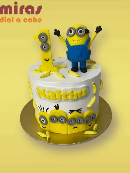 Bello! This Minion-themed cake is perfect for a first birthday. It features a cheerful Minion topper, lots of bananas, and other Minions peeking around the side.