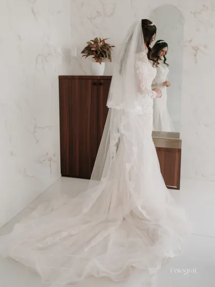 A full-length shot of the bride looking in the mirror, showing off the magnificent train of her white wedding gown.