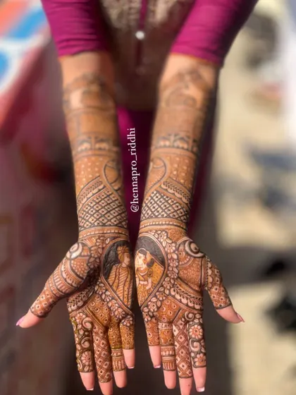 A lovely portrait of a bride and groom nestled within a heart shape on the palm. This is a classic and romantic way to feature the couple in the bridal mehendi design.