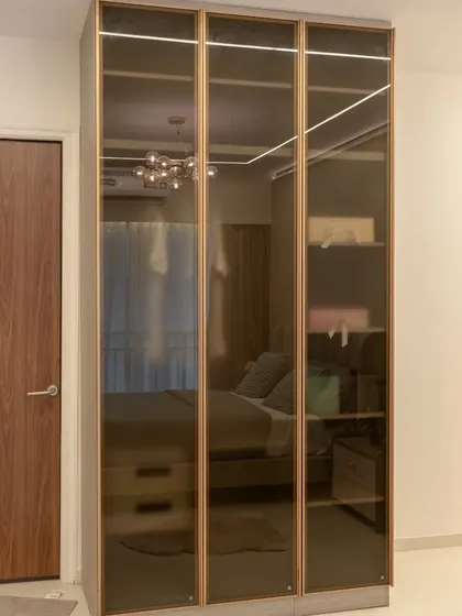 This bedroom features a wardrobe with tinted glass doors, which adds a sense of depth and allows for a subtle display of the contents inside.