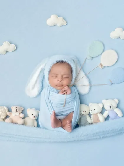 This little bunny is floating away with balloons, surrounded by teddy bears. It's a creative and imaginative setup for a newborn boy.