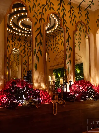 Hand-painted details by local artists adorned the walls at our 'Mid-Century Mod' event. This corner features deep red florals against a backdrop of painted vines and mirrored arches, creating a warm and tranquil space.