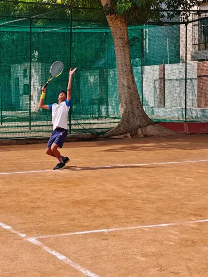 A junior player practicing his serve on the clay court. The classic clay surface is excellent for developing stamina and learning to construct points.