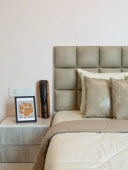 This bedroom features a plush, tufted headboard in a neutral grey, creating a comfortable and sophisticated backdrop for rest and relaxation.