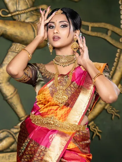 A powerful pose from the model, showcasing the grandeur of the traditional temple jewellery against a sculpture of Nataraja.