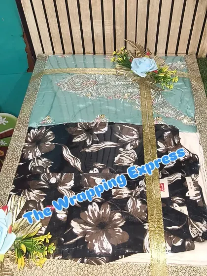 A tray containing multiple clothing items, packed neatly with a golden ribbon and blue flowers.