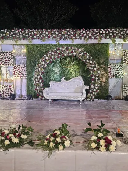 A clear, frontal shot of the outdoor stage, highlighting the intricate floral work on the arch and side panels.