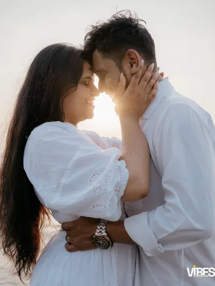 An intimate close-up of a couple touching foreheads on the beach, with the setting sun creating a beautiful flare behind them. This silhouette-style shot is all about connection and romance.