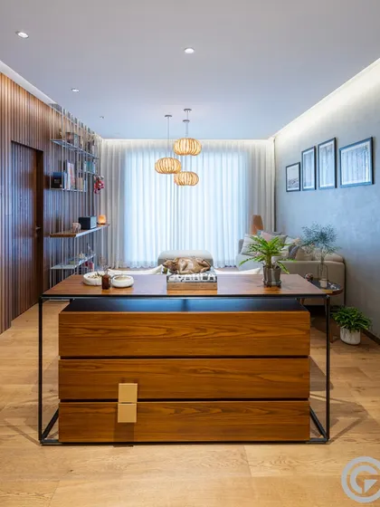 A custom-designed chest of drawers, crafted from wood with a sleek metal frame, acts as a functional divider between the living and dining areas. It defines the space without creating a solid visual barrier.