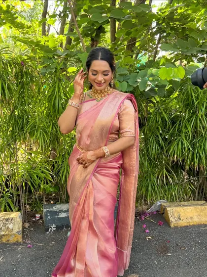 A full length shot showing how the soft pink saree and the glowing makeup create a harmonious and elegant look.