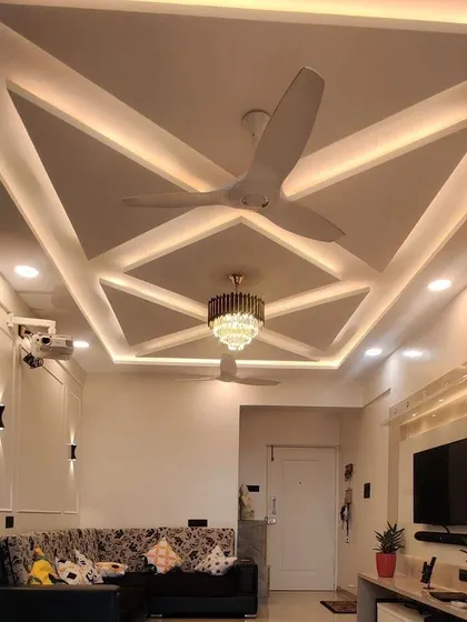 A completed project showing a geometric false ceiling design with integrated cove lighting and a central chandelier. This is how I use POP work to add drama and elegance to a living room.