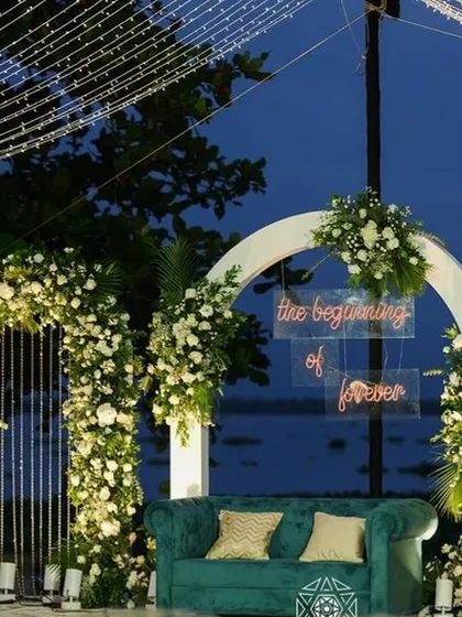 A romantic lakeside photo booth with a neon sign that reads 'the beginning of forever'.