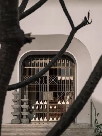 A view of the entrance gate, with its contemporary take on traditional Kutch textile patterns, framed by the branches of a frangipani tree.