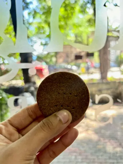 Holding up one of my Millet Jaggery cookies against the light. You can see the rustic, wholesome texture. I'm always looking for feedback on these healthier treats.