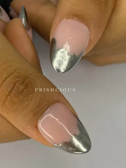A close-up of these oval-shaped press-on nails with a melted silver chrome tip design. This is such a cool and edgy take on a French manicure.