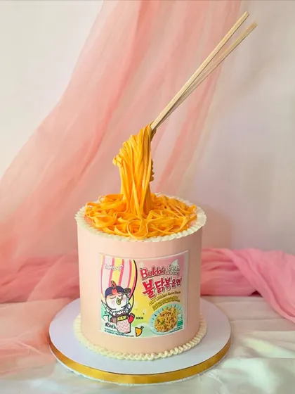 This version of the ramen cake is inspired by the popular cheesy Buldak noodles. The "floating" chopsticks and detailed packaging are all part of the edible illusion.