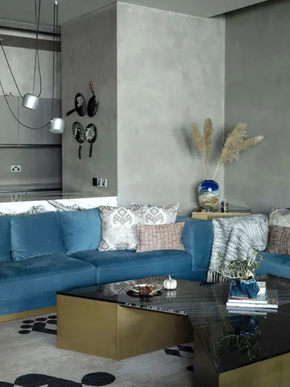 A comfortable blue sofa and a 'Kolam' rug from Jaipur Rugs create a warm and inviting ambiance in the family lounge. The space is designed for relaxed family moments, combining functionality with aesthetic finesse.