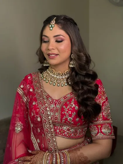 Another angle of this beautiful red bridal look, showing the soft waves in her hair and the flawless finish of the makeup, which is designed to last through all the ceremonies.