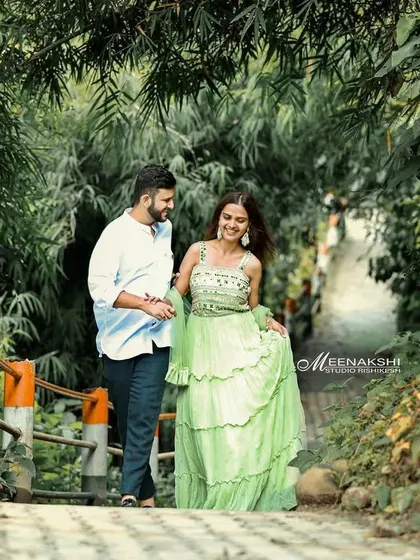 A couple shares a happy walk along a tree-lined path in Rishikesh. The vibrant green of the surroundings and the bride's dress create a fresh and lively image.