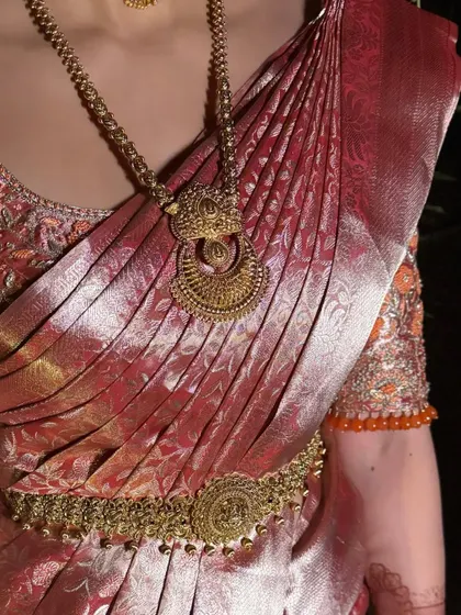 A close-up of the bride's traditional attire, showing the perfect saree pleats and the stunning temple jewellery.
