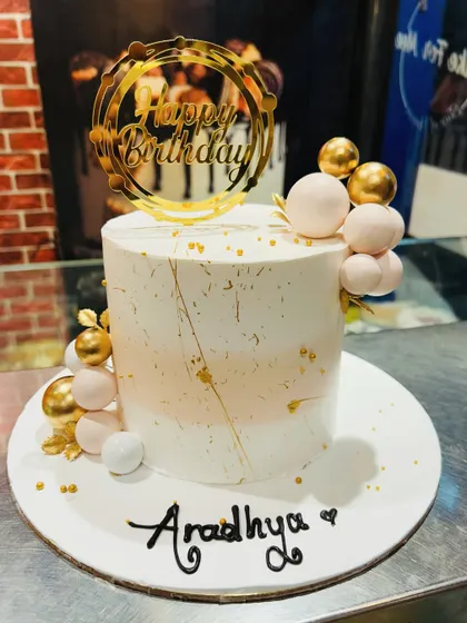 A chic and modern birthday cake with a white and rose gold color scheme and abstract gold details.