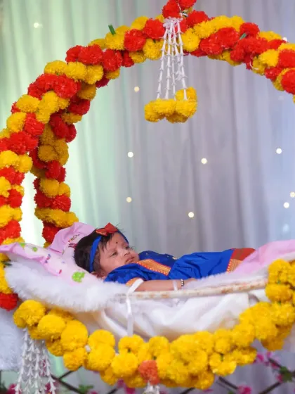 A peaceful shot of a newborn sleeping in a beautifully decorated cradle during a traditional naming ceremony. The cradle is adorned with bright marigold flowers, adding a vibrant, cultural touch.