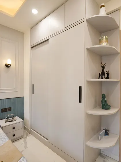 Smart storage is key in any bedroom. This design includes a sleek sliding wardrobe with integrated corner shelves for displaying decor items.