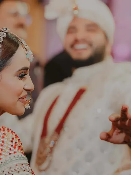 Happily ever after begins with a click. A candid shot of the bride with the groom joyfully dancing in the background.