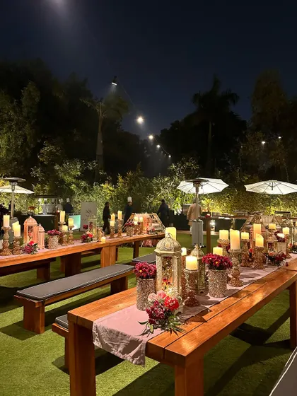 Long community tables set up on the lawn, decorated with candles and flowers for a family-style dinner.