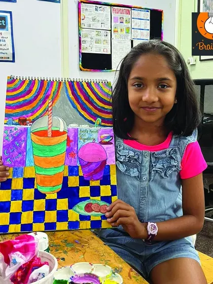 A young student proudly displays her colorful still life painting. Our classes are designed to be fun and encouraging, nurturing a lifelong love for art.