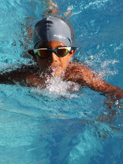 A focused swimmer coming up for air during a breaststroke lap.