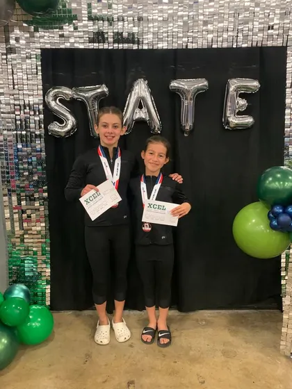 Two of our Xcel athletes showing off their medals and certificates after a successful State meet.