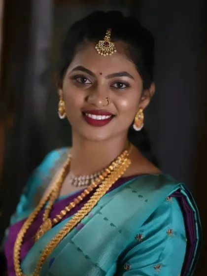 A beautiful, smiling portrait of a happy client. The combination of a teal saree and a bold red lip is striking and joyful.
