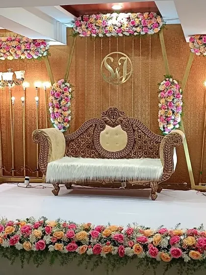 This engagement stage features a rich, textured gold backdrop with beautiful pink and peach floral arrangements. The design is both classic and modern, suitable for a variety of celebratory events.