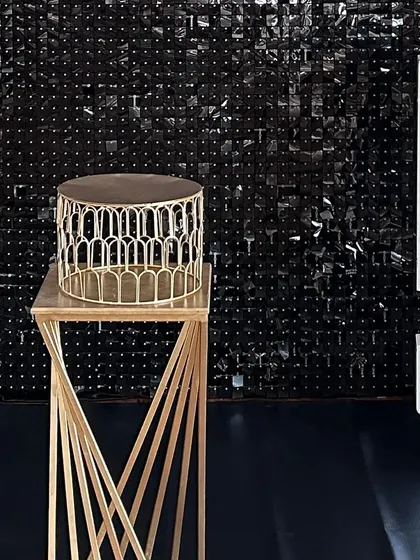 A modern gold cake stand on a twisted pedestal, set against a black shimmer wall. This highlights the high-quality props I use to complement my decorations.