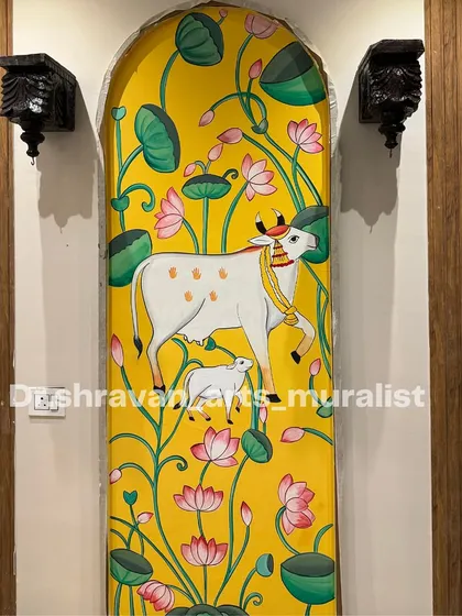 This Pichwai art was designed for a foyer area. The tall, narrow composition featuring a cow and calf amidst a field of lotuses is a perfect fit for the arched niche.