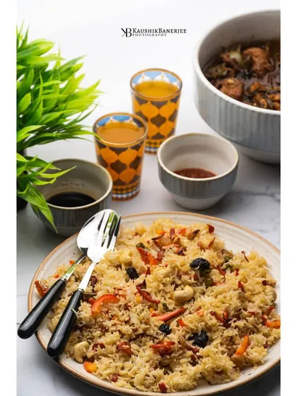 A plate of Bengali-style fried rice served with a side of chili fish. This bright, clean shot highlights the colors and textures of this popular Indo-Chinese meal.