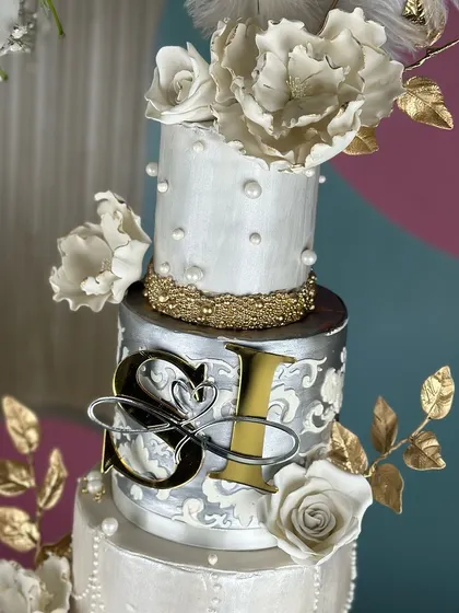A masterpiece for a love that shines. This silver and pearl-themed wedding cake, framed by a floral hoop, combines intricate textures, delicate sugar flowers, and shimmering details for a look of timeless elegance.