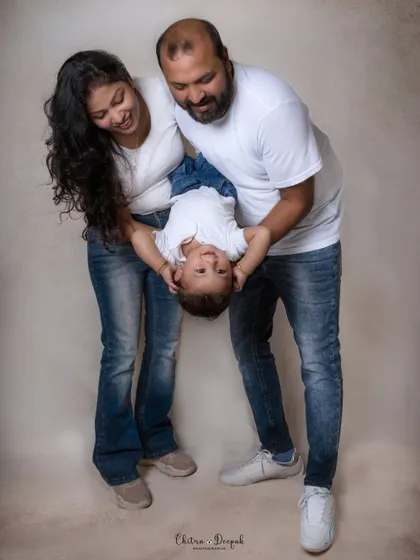 A playful family photo where the parents are holding their laughing baby upside down, capturing a moment of pure fun and connection.