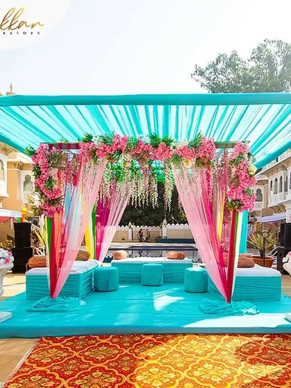 A beautiful Haldi or Mehendi seating area by the pool, decorated in shades of turquoise and pink. The setup is both colorful and elegant, perfect for a day event.