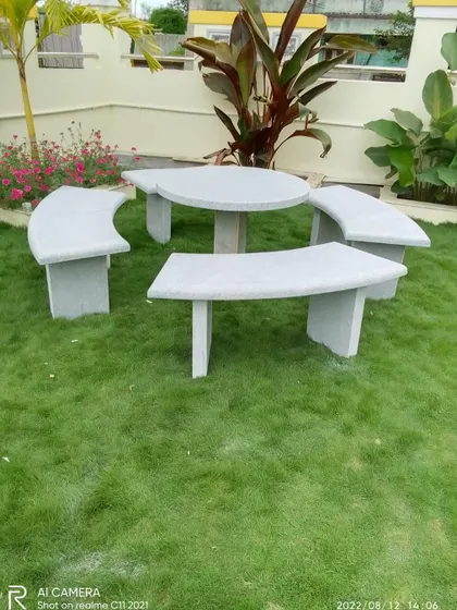 A complete garden seating set made from stone, including a round table and four curved benches. This creates a permanent and weather-proof dining or conversation area in the garden.