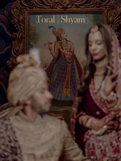 An artistic, moody portrait of the couple at their royal Mumbai wedding, with a traditional painting in the background adding to the regal theme.