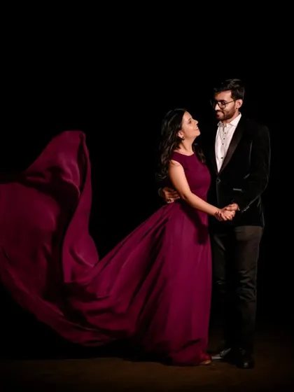 A dramatic studio shot that feels like a movie poster. The flowing wine-colored trail gown adds movement and elegance to this couple's intimate pre-wedding portrait.
