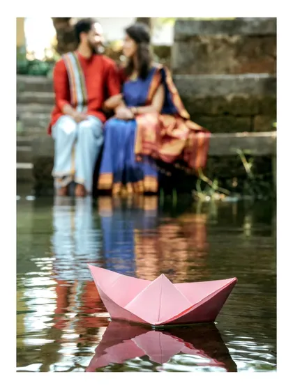 A creative and artistic pre-wedding photo. Using elements like this simple paper boat, I aim to tell a visual story of the couple's journey, set against the calm waters of a traditional temple pond.