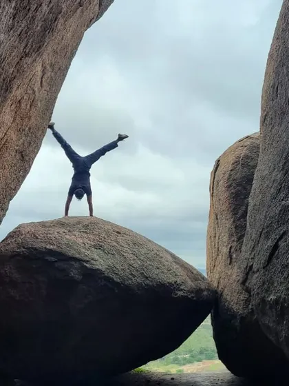 Akash doing a handstand on a perched boulder, a playful display of his strength, balance, and love for the outdoors.