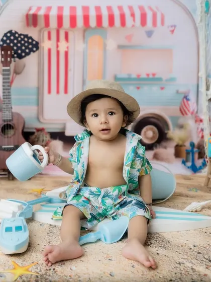 The perfect setup for a summer-themed milestone, with a camper van, ukulele, and sandy floor.